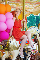 Attractive girl having fun in the park riding a carousel 