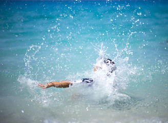 Unrecognizable girl splashing in crystal clear blue sea water. 