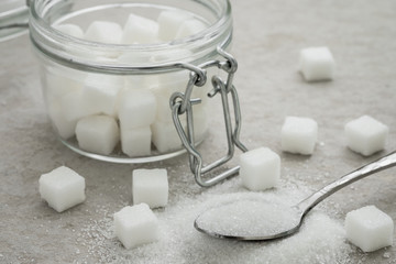 Sugar on spoon and glass jar