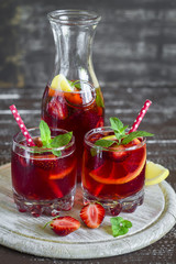 strawberry lemonade with lemon and mint in glass beakers on a light surface