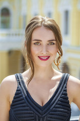 Young beautiful woman in black dress posing outdoors in sunny we