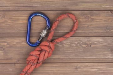 Obraz premium Figure eight knot with climbing carabiner on wooden background. The concept of selling advertising space for climbing equipment.