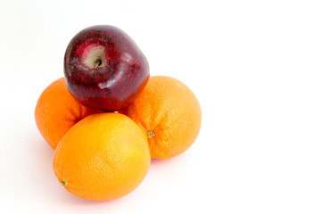 Three navel oranges with a red delicious apple on top