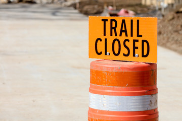 Orange trail closed sign on a traffic drum in a construction zone