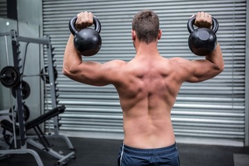 Fototapeta na wymiar Muscular man lifting two kettlebells