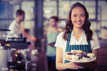 Pretty waitress showing a plate of cupcakes