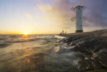 Sunset on the coast, lighthouse windmill in Swinoujscie, Poland. 