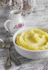 mashed potatoes in a white bowl on a light wooden background