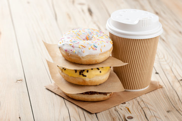 Colorful donuts and paper cup on wooden table