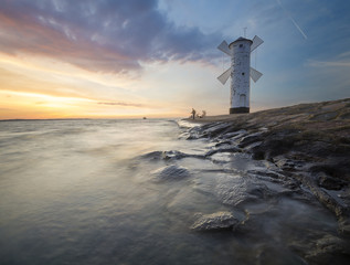Sunset on the coast, lighthouse windmill in Swinoujscie, Poland. 