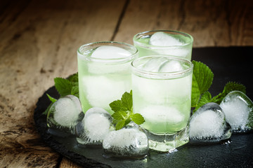 Green cold drink with ice in a heart shape, selective focus
