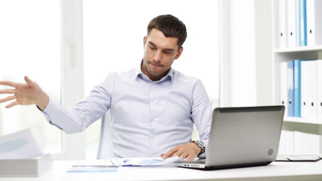 busy businessman with laptop and papers in office