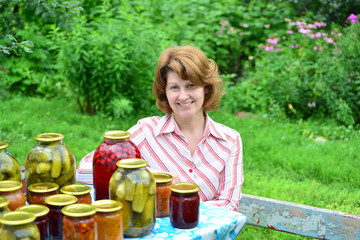 Housewife with homemade pickles and jams in  garden