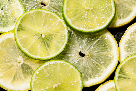 Sliced lemon and lime on a dark background, top view, selective