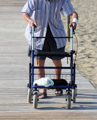 Obraz premium elderly man walking with Walker on the beach