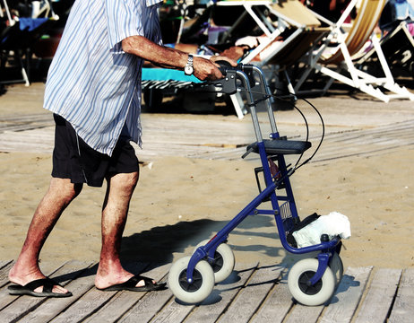 elderly man walking with Walker on the beach