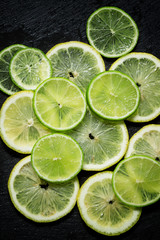 Sliced lemon and lime on a dark background, top view, selective