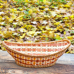 Fototapeta na wymiar Empty basket on old wooden table.In the background blurred autumn leaves