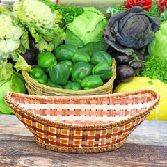 Fototapeta na wymiar Empty basket on old wooden table.In the background blurred lot of ripe vegetables