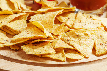 Nachos, tomato sauce, tomatoes, greens, lime on a wooden table,