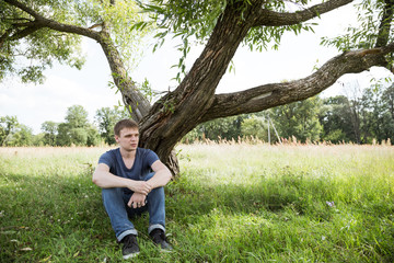 Sad guy sitting under a tree