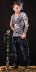 Tattooed man smoking traditional hookah.