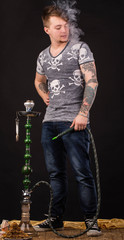 Tattooed man smoking traditional hookah.