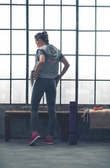 Fototapeta na wymiar Rear view of woman in workout gear in city loft gym