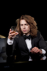 Elegant young man holding a glass of brandy looking away