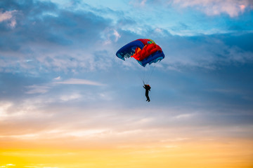 Skydiver On Colorful Parachute In Sunny Sky