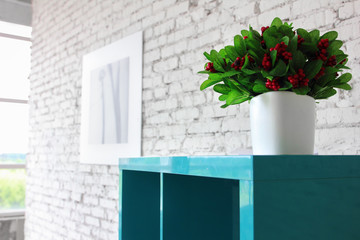 Interior in white brick, blue shelves and vase with artificial branches cranberries