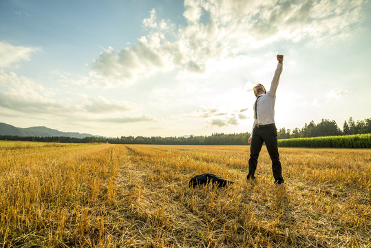 Businessman in the Field Raising Arm for Success