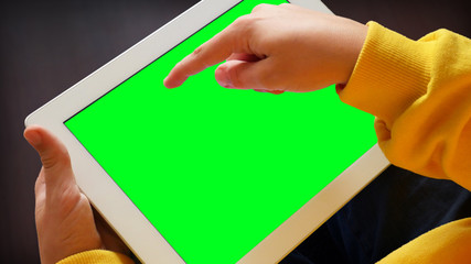 Hand of a child tapping on tablet computer screen, greenscreen, close