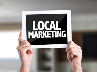 Tablet pc with text Local Marketing on a house background