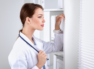 Woman doctor is standing near window 