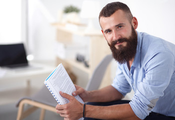 Fototapeta premium Young businessman sitting on chair with book in office