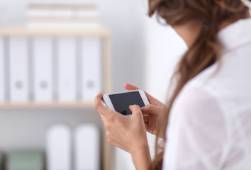 Businesswoman sending message with smartphone sitting in the