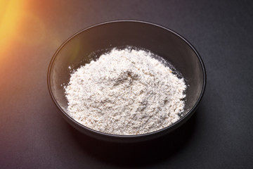 black asian bowl with flour on black background