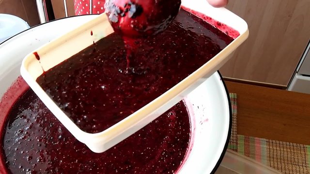 Woman lays out blackcurrant jam in a plastic box