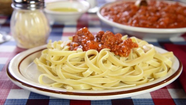 Pouring spaghetti sauce onto pasta
