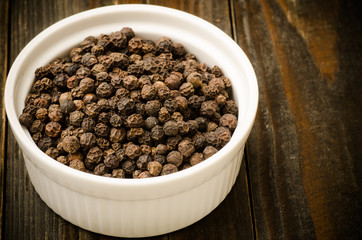 Black pepper in the bowl on wooden background,food ingredient