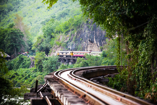 Trains run on tracks through the woods and cliffs 