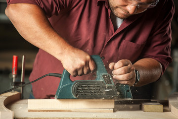 Carpenter working with electric planer.