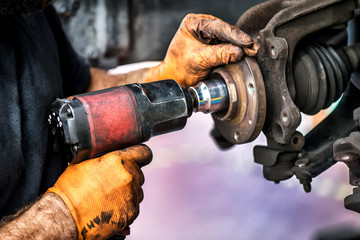Powerful mechanic hand drilling on a car wheel