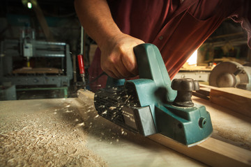 Carpenter working with electric planer. - obrazy, fototapety, plakaty