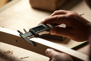 Carpenter measuring chair part with electric callipers.