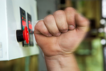 Male hand pushing emergency stop button.