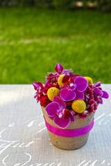 Floral arrangement with purple orchids and yellow craspedias.