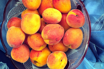 Ripe peaches in a bowl with a blue scarf on a marble tableRipe peaches in a bowl