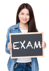 Young woman hold with chalkboard showing a word exam